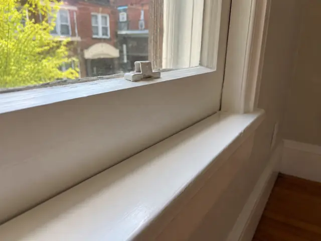 The same style of wooden window sash with smooth, intact paint and a clean sill